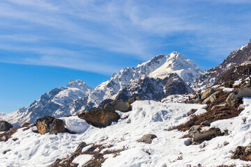 Snow-covered mountain range with rocky outcrops beneath a clear blue sky. Majestic peaks dominate...
