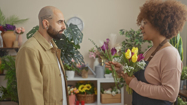 A man buys flowers from a woman florist in a well-decorated indoor flower shop. - Powered by Adobe