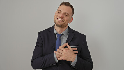 Handsome man in suit with hands on heart smiling over white background
