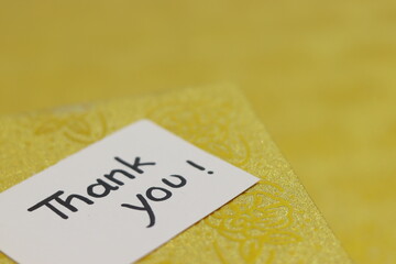 Thank you hand written notes with golden gift box in background.