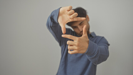 A young man framing his face with hands against a white background