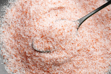 Crushed Himalayan pink mineral salt in a metal spoon. Fresh raw exotic culinary ingredient. Top view. 