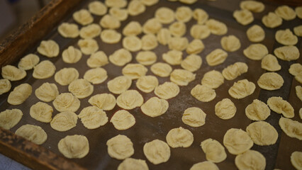 Close-up of traditional italian orecchiette pasta drying on a wooden tray outdoors in bari, puglia, capturing an authentic culinary moment in europe.