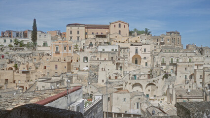 A panoramic view of the historic town of matera in basilicata, italy, showcasing its charming stone buildings and blue sky in the background.