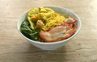 Chinese egg yellow noodles with red barbecue pork and dumpling in clear soup on bowl