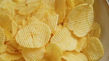 Crispy potato chips displayed in a closeup shot highlighting golden texture and ridges.