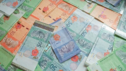 Malaysian banknotes of various denominations are scattered across a flat surface, highlighting the vibrant colors and detailed designs of malaysia's ringgit currency.