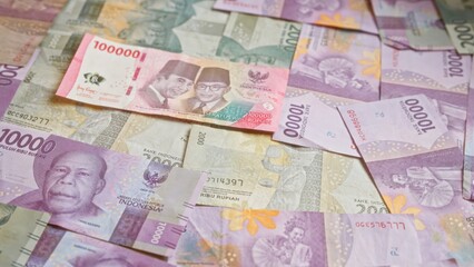 Indonesian rupiah banknotes spread out showing various denominations including 100000, 50000, 20000, and 10000 in a colorful, detailed manner.