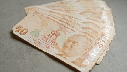 Turkish fifty lira banknotes fanned out on a concrete surface, showing detailed currency features and national emblem from turkey.