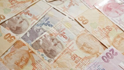 Turkish banknotes displaying different denominations of lira currency scattered, showcasing turkey's paper money used in financial transactions.