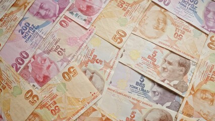 Turkish lira banknotes scattered across the image showcase various denominations, displaying vibrant colors and detailed portraits, emphasizing the financial theme from turkey.
