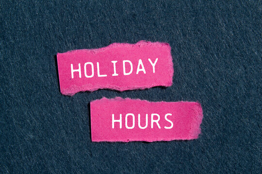 Holiday hours message written on ripped pink torn paper pieces with gray felt background. Conceptual holiday hours symbol. Copy space.