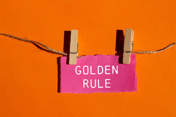 Golden rule message written on ripped torn pink paper piece with orange background. Conceptual...