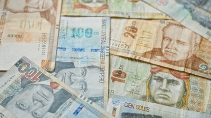 Colorful peruvian banknotes of various denominations spread out, showcasing prominent figures and intricate designs representative of peru's currency.