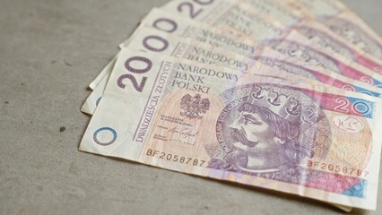 Polish banknotes, including 20 zloty, laid on a concrete surface, highlighting the currency of poland in a financial context.