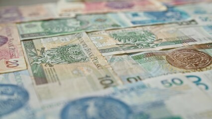 Polish banknotes of various denominations scattered closely on a table showcasing detailed designs and colors of zloty currency in poland.