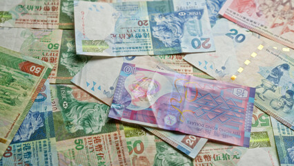 Hong kong dollar bills scattered on a surface showcasing different denominations and colorful designs.