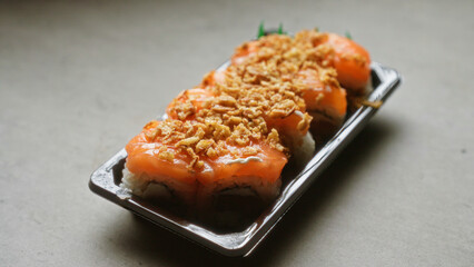 Sushi plate featuring fresh salmon with crispy toppings on a light background