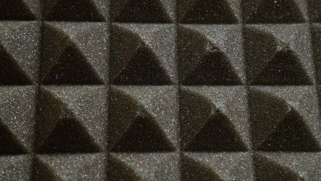 Closeup of black acoustic foam panels with a textured surface arranged in a pattern for soundproofing and noise reduction in a studio or recording environment