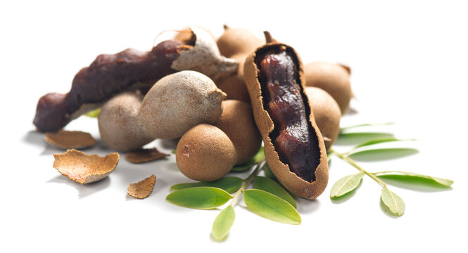 Tamarind tropical fruits isolated on white background. Fresh Tamarind pods with leaves (Tamarindus indica, Indian date), healthy vegan food close up 