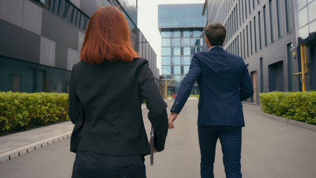 Back view worker two partners people business colleagues coworkers businessman businesswoman walk in city late man motivate woman hurry rush running to urgent meeting at office run together hurrying