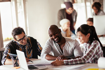 Designer team collaborating on project with blueprints in office