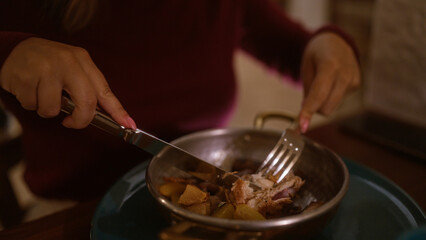 Woman enjoying a meal at an indoor restaurant in italy, dining on a flavorful dish with focus on her hands using fork and knife.