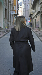 Back-view of a young adult brunette woman walking through a historic street in istanbul.