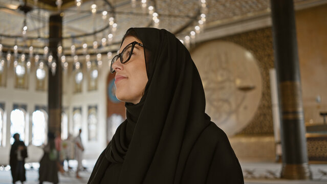 A contemplative woman in a hijab admires the ornate interior of a doha mosque representing islamic architecture and culture.