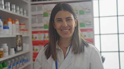 Smiling woman pharmacist standing inside a drugstore with shelves of medications