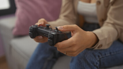 A young woman is playing a video game with a controller in her hands while sitting in a cozy living room. © Krakenimages.com