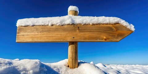 Wooden signpost blanketed in snow against a backdrop of a clear blue sky
