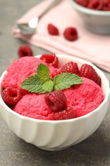 Delicious raspberry sorbet, fresh berries and mint in bowl on gray textured table, closeup