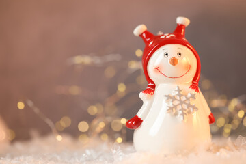 Funny snowman figure on artificial snow against blurred lights