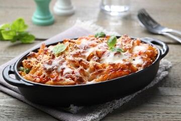 Delicious al forno pasta in baking dish on wooden table, closeup