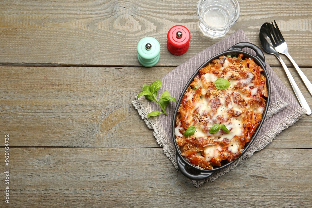 Poster Delicious al forno pasta in baking dish on wooden table, flat lay. Space for text