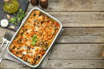 Delicious al forno pasta in baking dish on wooden table, flat lay. Space for text