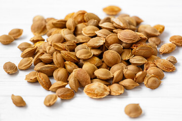 A pile of apricot pits on a light background. View from above. Vitamin B 17. Healthy food.