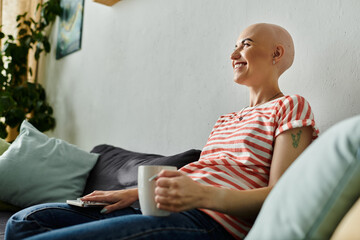 A cheerful bald woman enjoys a peaceful moment, sipping a warm beverage on her couch.