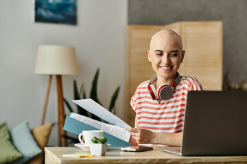 The bald woman smiles while organizing materials at her modern desk, surrounded by greenery.