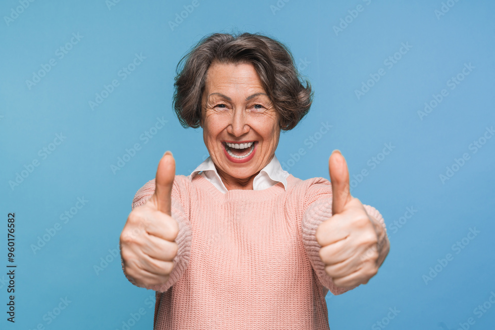 Wall mural mature satisfied happy smiling caucasian woman female pensioner in casual clothes showing two thumb 