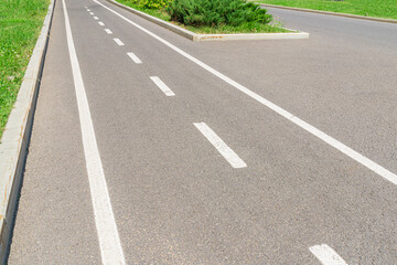 asphalt road with white road markings and paving stone