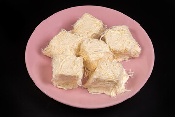 Traditional Turkish sweets pishmanie on pink dish on black background