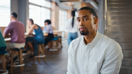 Fototapeta premium Portrait Of Serious Young Businessman Working In Busy Modern Office With Colleagues In Background