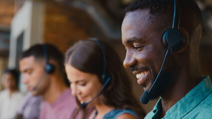 Close Up Of Multi-Cultural Customer Support Or Telesales Team In Modern Office Wearing Headsets