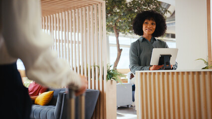 Close Up Of Businesswoman With Suitcase Checking In At Hotel Reception For Conference
