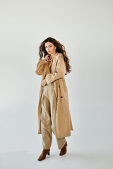 A beautiful young woman poses confidently in a trendy autumn outfit, embodying elegance and style in a bright studio.