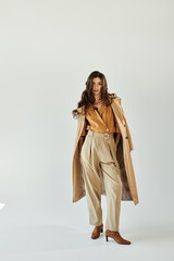 In a serene studio, a beautiful young woman confidently models her chic autumn attire, embodying seasonal elegance.