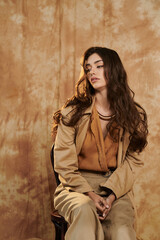 Fototapeta premium A beautiful woman elegantly poses in a chic autumn outfit, highlighting seasonal style and warmth in a cozy studio environment.
