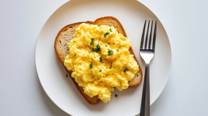 Softly scrambled eggs on toast bread with fork beside it on a white background 